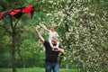 Walking around. Running with red kite. Child sitting on the man`s shoulders. Having fun