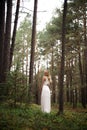 Walking Beautiful young blonde woman forest nymph in white dress in evergreen wood Royalty Free Stock Photo