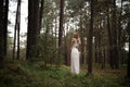 Walking Beautiful young blonde woman forest nymph in white dress in evergreen wood Royalty Free Stock Photo