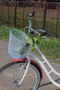 A walking bike is at the bus stop. In the basket is a bouquet of flowers