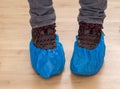 Walking boots and feet in blue plastic shoe protectors, covers. Hygiene in medical situations etc. Single use Royalty Free Stock Photo