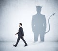 Walking businessman with devil shadow