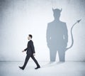 Walking businessman with devil shadow Royalty Free Stock Photo