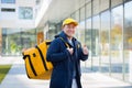 Walking courier delivery man asian smiling and looking at camera, has a big yellow backpack for food delivery Royalty Free Stock Photo