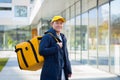 Walking courier delivery man asian smiling and looking at camera, has a big yellow backpack for food delivery Royalty Free Stock Photo