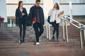 Walking down the stairs. Three young students are outside the university outdoors Royalty Free Stock Photo