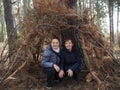 Walking elderly people in the autumn forest. Imitation of a hut made of branches. They look at the camera with optimism Royalty Free Stock Photo