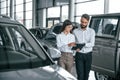 Walking forward and talking. Man with woman in white clothes are in the car dealership together Royalty Free Stock Photo