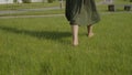 Walking girl with bare feet on a green lawn. On a clear sunny summer day