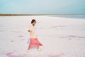 Walking girl in big sweater and blowing pink dress at beautiful landscape of salt flats at pink lake, feeling alive and