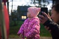 Walking girls with her daughter in the evening city and talking on the video communication with her father.