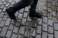 Walking man`s legs at wet cobblestone square after rain. Old tile road. Royalty Free Stock Photo