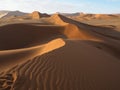 Walking on natural curved ridge line through wind blow pattern of rusty red sand dune with shade and shadow on desert landscape Royalty Free Stock Photo