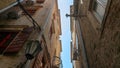 Walking on old town narrow street and looking up at the tiled roof and stone walls of ancient buildings and houses Royalty Free Stock Photo