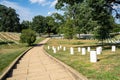 A walking path leads through Arlington National Cemetary in Arlington Virginia, with rows of white stone, military grave markers Royalty Free Stock Photo