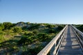 Wooden foot path over the sand dunes at the beach on a sunny day. Royalty Free Stock Photo