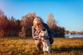 Walking pug dog in autumn park by river. Happy woman hugging pet and having fun with best friend Royalty Free Stock Photo