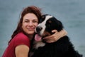 Walking and relaxing with large dog on warm summer morning. Caucasian pretty red haired woman and Bernese Mountain Dog embrace