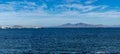 Walking on sea promenade in Corralejo along black rocks, blue water, view on Lanzarote island, Fuerteventura, Canary islands, Royalty Free Stock Photo