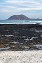 Walking on sea promenade in Corralejo along black rocks, blue water, view on Lobos island, Fuerteventura, Canary islands, Spain Royalty Free Stock Photo