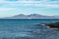 Walking on sea promenade in Corralejo along black rocks, blue water, view on Lanzarote island, Fuerteventura, Canary islands, Royalty Free Stock Photo