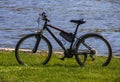 Walking tourist bike stands on the grass by the river