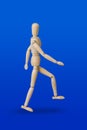 Walking wooden toy figure on blue