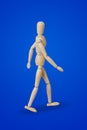 Walking wooden toy figure on blue