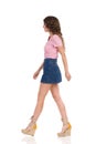 Walking Young Woman In Jeans Mini Skirt And Wedge Shoes. Side View Royalty Free Stock Photo