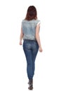 Walking Young Woman In Jeans Vest And Black Boots. Rear View