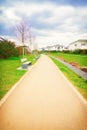 Walkway with benches in nature, park green meadow grass between quiet settlement with family houses for walks Royalty Free Stock Photo