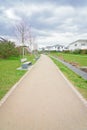 Walkway with benches in nature, park green meadow grass between quiet settlement with family houses for walks Royalty Free Stock Photo