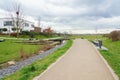 Walkway with benches in nature, park green meadow grass between settlement with family houses for walks, bridge over a stream Royalty Free Stock Photo