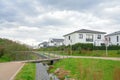 Walkway with benches in nature, park green meadow grass between settlement with family houses for walks, bridge over a stream Royalty Free Stock Photo