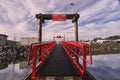 A walkway with bright red railings contrasts against a dramatic sky at a local marina.