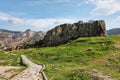 Walkway in green landscape under blue sky with white fluffy clou Royalty Free Stock Photo