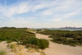 Walkway in the sand between plants, dunes of the sandy beach and view on the dock and canal, Hoek van Holland Royalty Free Stock Photo