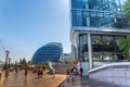 Walkway at southwark banks with people and view of the modern building of city hall and office buildings on river Thames in London