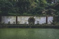 Wall with arched opening in the park with pond covered with green algae Royalty Free Stock Photo