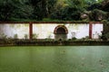 Wall with arched opening in the park with pond covered with green algae. Royalty Free Stock Photo