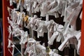 Wall of bad fortune O-mikuji in front of Japanese temple with strips of paper describing bad luck