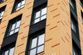 The wall of a brick multistoried building with transparent windows. Geometric abstract pattern. House facade texture, background Royalty Free Stock Photo