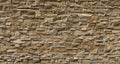 Wall cladding in brown natural stone made from bricks of irregular shape.