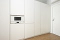 Wall covered with white kitchen cabinets and a matching microwave