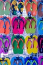 A wall display of colourful flip flops for sale, colours include, green, red and yellow