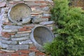 A wall of flat granite stones with embedded pots and twined with thuja branches Royalty Free Stock Photo