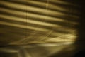 Wall with golden light and black shadows from blinds