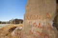 Wall with graffiti and ruins of Saint Mamas gothic church in the background in the abandoned village of Agios Sozomenos, Cyprus