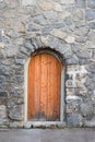 Wall with grey natural stones and wooden arched door