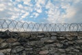 A wall of grey stone topped with barbed wire. Royalty Free Stock Photo